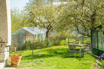 Wooden garden furniture stands in a spring garden against . vegetable garden