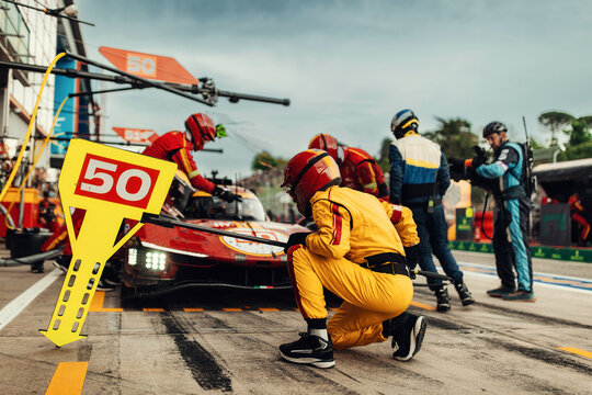 Team Mechanics refuel During a High-Speed Pit Stop in the Midst of an Endurance Race. Supercar do a inspection on pit lane during race