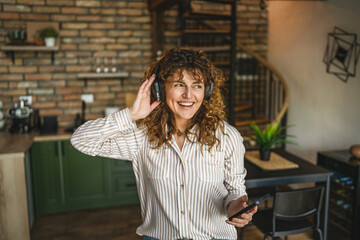 cheerful woman use mobile phone and headphones listen music and dance