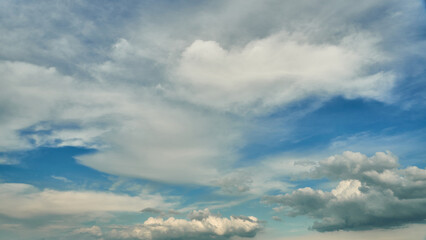 White fluffy clouds in the sky. Blue sky and cloud cover on a sunny summer day. Empty background,...