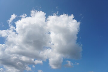 White fluffy clouds in the sky. Blue sky and cloud cover on a sunny summer day. Empty background, copy space
