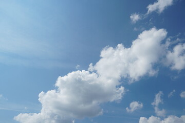 White fluffy clouds in the sky. Blue sky and cloud cover on a sunny summer day. Empty background, copy space
