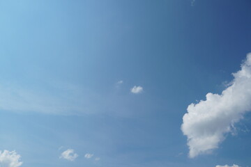 White fluffy clouds in the sky. Blue sky and cloud cover on a sunny summer day. Empty background, copy space