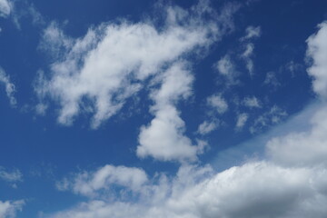 White fluffy clouds in the sky. Blue sky and cloud cover on a sunny summer day. Empty background, copy space