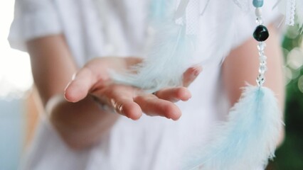 Woman making dreamcatcher from threads, feathers, beads and silk ribbons, making home decor items,...