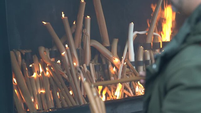Pray by throwing large candles into the burning fire, Sanctuary of Fatima, Portugal