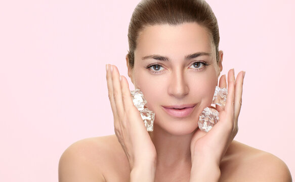 Woman practicing skincare with ice cubes on face for refreshing beauty treatment