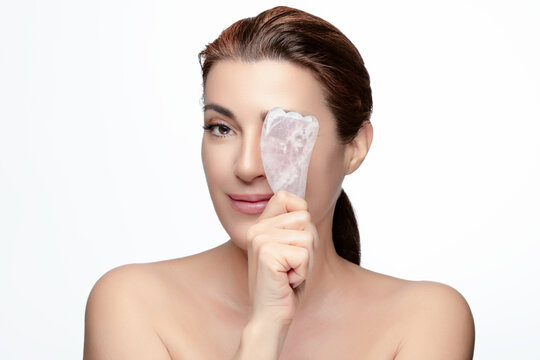 Woman demonstrating gua sha tool for facial massage