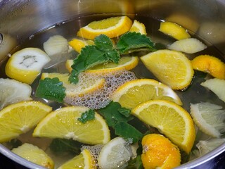 Homemade lemonade. Orange, lemon and mint pieces in large container with spring water