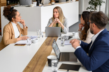 Group of business professionals analyzing data and collaborating on growth plans in board room during meeting