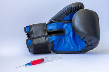 Blue boxing glove next to syringe with red liquid on white background