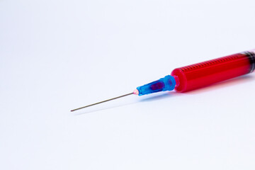 Fototapeta premium Close up of plastic syringe and blue steel needle filled with red liquid