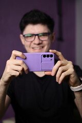 Man wearing glasses looking at smartphone screen with happy expression