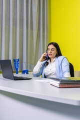 Businesswoman working at office desk and making a phone call