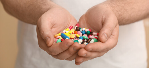 Man with many different pills in hands, closeup