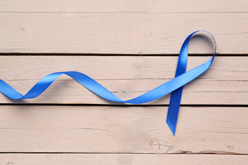 Blue satin ribbon on light wooden background. Prostate cancer concept