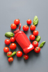 Bottle of ketchup and tomatoes on grey background