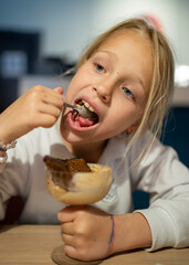 Young girl enjoying a unique dessert of ice cream topped with a slice of Borodino rye bread, experiencing an unusual flavor combination in a modern restaurant setting
