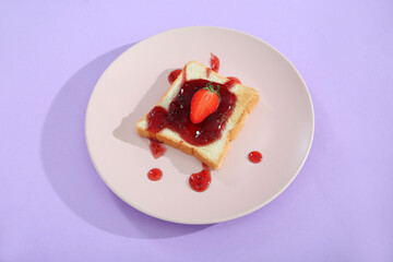 Plate of delicious toast with strawberry jam on lilac background