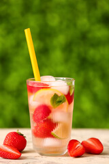 Glass of strawberry lemonade on white table outdoors