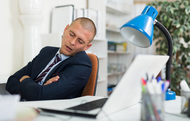 Fototapeta premium Tired businessman fell asleep in armchair in modern office