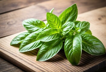 A bunch of fresh basil leaves on a cutting board.