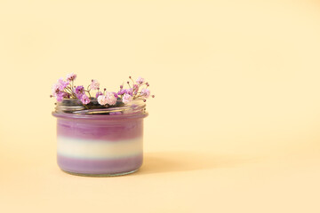 Glass of panna cotta with blueberry and beautiful gypsophila flowers on beige background
