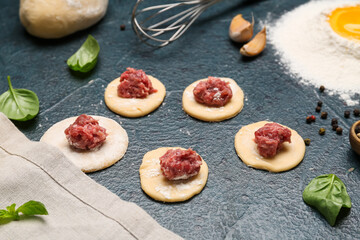Raw dough with minced meat for preparing dumplings on black background