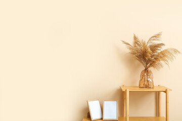 Vase with dried pampas grass on shelving unit near beige wall