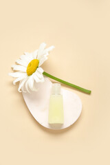 Plaster podium with bottle of cosmetic product and chamomile flower on color background
