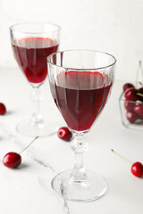 Glasses of sweet cherry liqueur with fresh berries on white grunge background
