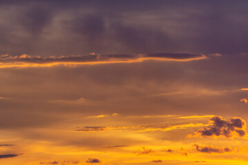 Sunset overlooking a sky full of orange, gold and purple hues, with delicate clouds creating a picturesque landscape