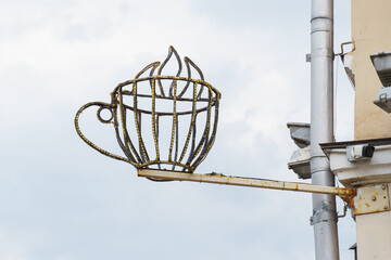 Creative metal sculpture of a steaming cup mounted on a building exterior