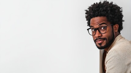 Obraz premium Portrait of a Young Black Man with Glasses Looking Over a Wall Stylish Casual Beige Shirt Happy Smiling Expression Natural Hair Studio Shot Modern Photography High Quality Image Professional Headshot 