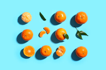Many sweet mandarins with leaves on blue background