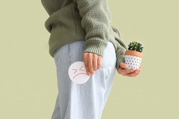 Mature woman with sad smile and cactus on green background, closeup. Hemorrhoids concept © Pixel-Shot