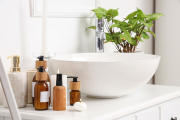Bottles of skincare products near sink on table in bathroom
