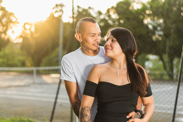 young colombian couple, young man hugging his girlfriend from behind while looking into her eyes, young college couple in love