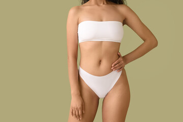 Beautiful young African-American woman with stretch marks on her body against green background,...