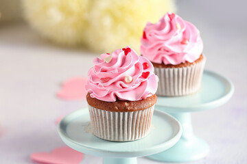 Stand with tasty cupcakes for Valentine's Day on light background