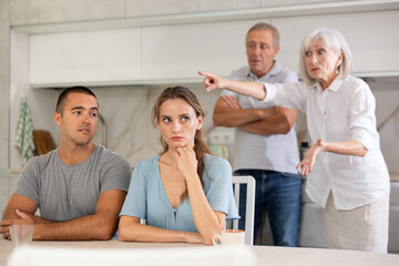 Elderly parents make claims to young couple in home kitchen