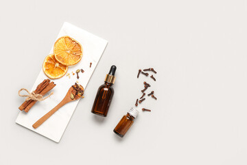 Tray with different spices and bottles of essential oil on white background