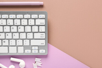 Grey computer keyboard, felt-tip pen and earphones on brown lilac background. Top view