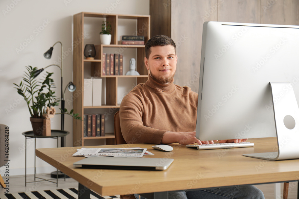 Poster young bearded man using computer at table in office