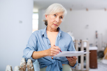 Portrait of elderly woman filling documentation during repair works in construction site