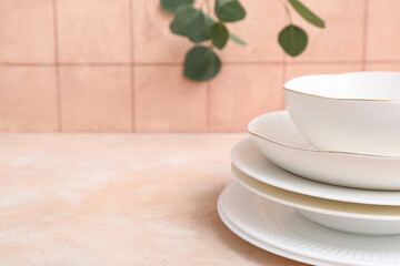 Beautiful tableware and leaves on table near orange tile wall