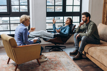 Teenage boy talking to female psychologist and his father during , therapy session