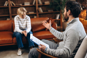 Fototapeta premium Upset mature woman attend therapy session with male psychologist