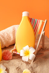 Naklejka na ściany i meble Bottle of sunscreen cream on deckchair, seashells and towel on sand against orange background