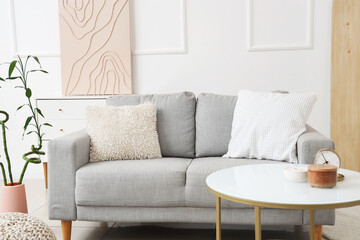 Comfortable sofa, coffee table and bamboo plant in interior of living room
